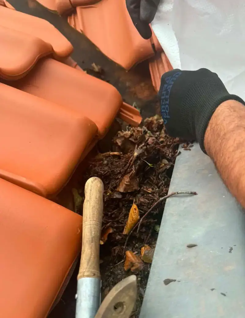Reinigen van de dakgoot tijdens de werkzaamheden